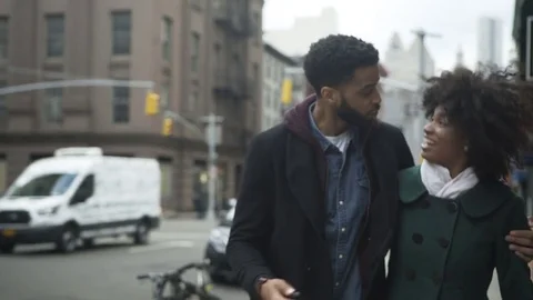 Dolly shot of laughing couple taking selfie while walking on footpath in city Stock Footage