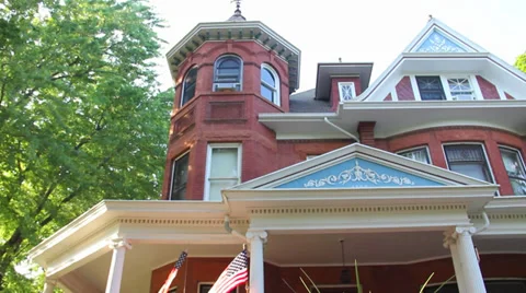 Dolly shot looking up at a large Victorian home with an American Flag waving Stock-Footage 39818375