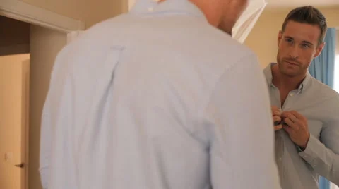 Dolly shot of man in bedroom getting dressed in mirror. Stock Footage 43665883