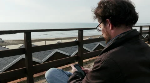 Dolly shot of man texting message in front of ocean 4K Stock Footage 58398289