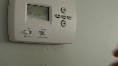 A dolly shot of a man turning down the temperature on thermostat Stock Footage 57758759