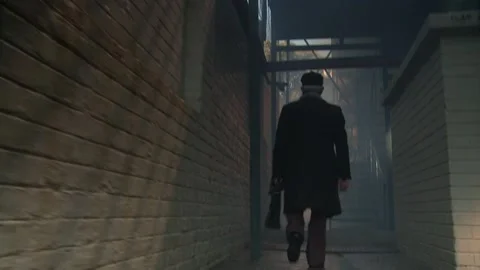 A dolly shot a man walking through a gloomy alley Stock Footage 311923964