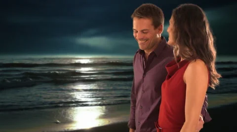 Dolly shot of mid aged couple walking on moonlit beach Stock Footage 43676073