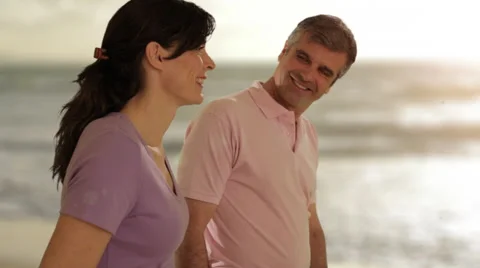 Dolly shot of mid aged couple walking in by beach Stock Footage 43676551