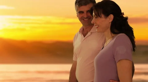 Dolly shot of mid aged couple walking in sunset Stock Footage 43676575