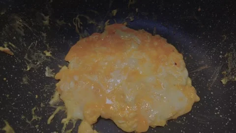 Dolly Shot of a Mixed Egg Cooking in a Speckled Non-Stick Pan Stock Footage 345133572