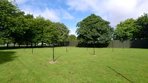 Dolly shot moving between old black washing poles on a large green. Video stock 200200845