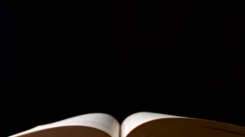 Dolly shot over open old book isolated on black background Stock Footage 147344243