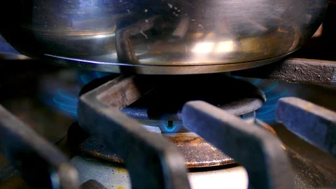 Dolly shot of a pan being placed onto the gas flame of a cooker. Stock-Footage 101795358