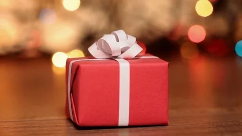 Dolly shot of red present box against blurry lights Stock Footage 81198390