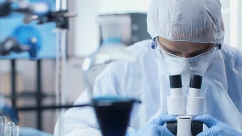 Dolly shot of scientist looking into a microscope in modern high end laboratory Stockbeeldmateriaal 108734369