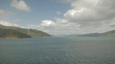 Dolly shot of sea by mountains against cloudy sky Stock Footage