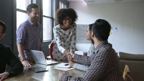 Dolly shot of smiling business people greeting at desk in office Stock Footage