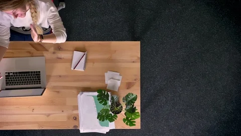 Dolly shot of top down view of casually-dressed woman talking in videochat using Video stock 99407472