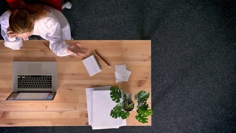 Dolly shot, top down view of ginger woman dressed in lab coat talking on Video stock 99422158