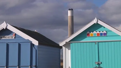 Dolly shot of two beach huts with power station in background Stock Footage