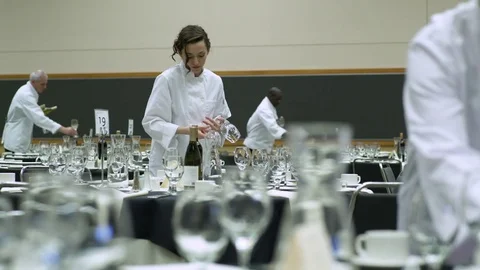 Dolly shot of waiters and waitresses setting tables in a venue 動画素材 77081380