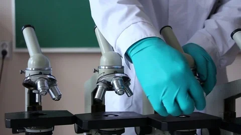 Dolly shot of working laboratory assistant wiping microscope lens Stock Footage 72822349