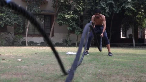 Dolly in shot of  young Athletic  Man Doing Battle Rope Exercise at home Stock Footage 144262044