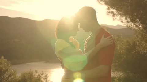 Dolly shot of young couple hugging overlooking lake in sunset. Stock Footage 43667533
