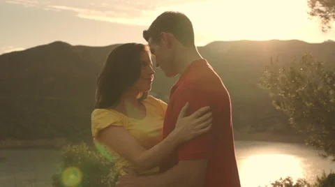 Dolly shot of young couple hugging overlooking lake in sunset. Stock Footage 43667558