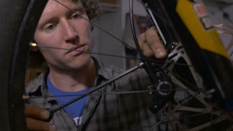 A dolly shot of a young man working on a bike in his workshop Stock Footage 69907735