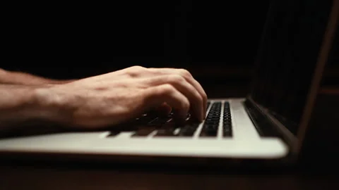 Dolly-in shot of young man working typing on keyboard laptop computer at dark Video stock 146543688