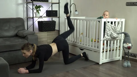 Dolly shot. Young mother performs an exercise at home. Stock Footage 125406780