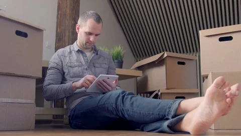 Dolly shot of young smiling man moving to a new house and using digital tablet Stock-Footage 72230342