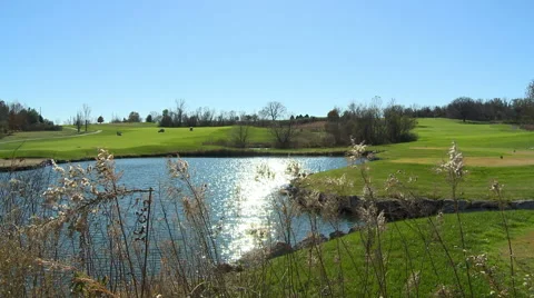A dolly slider establishing shot of a golf course with a small lake Stock Footage 57635446