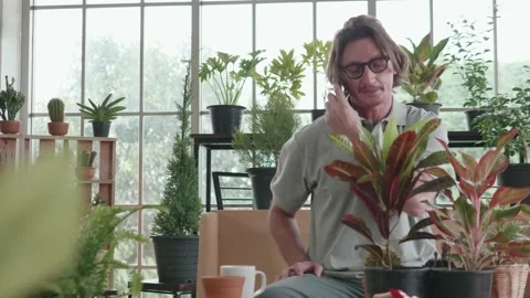 A dolly slider of a middle-aged man is talking on the phone in the living room. Stock Footage 140339993