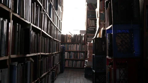 Dolly Through Bookstore Rows Of Stacks Full Of Books Low Angle Dim Stock Footage 136582713
