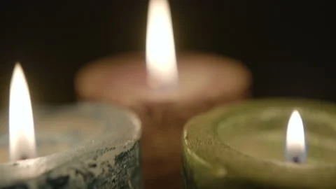 Dolly in through colored candles to close-up of flame Stock Footage 146994387