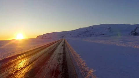 Dolly tracking POV front shot view of driving in a snowy country road at sunset Stock Footage 95196672