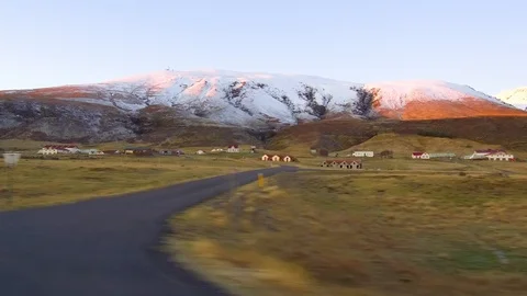 Dolly tracking shot driving alongside a meadow foothills houses with mountains Stock Footage 95197334