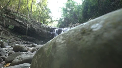 Dolly tracking shot of waterfall in rainforest with rocks in foreground Video stock 87188691