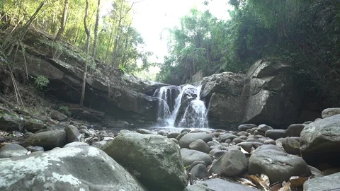 Dolly tracking shot of waterfall in rainforest with rocks in foreground Stock Footage 87189952