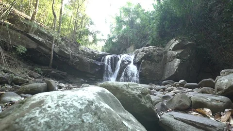 Dolly tracking shot of waterfall in rainforest with rocks in foreground Stock Footage 87190625
