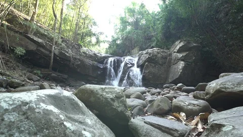 Dolly tracking shot of waterfall in rainforest with rocks in foreground Stock Footage 87221278