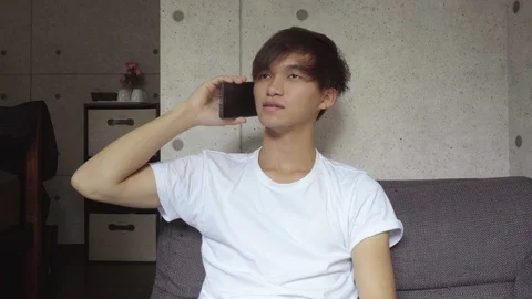 Dolly in - Young Japanese Man Calling On Smartphone At Home Stock Footage 104481944