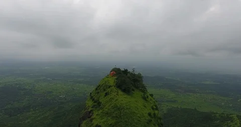 Dolly zoom in shot of a structure on top of a peak in a lush green forest Stock Footage 117018234