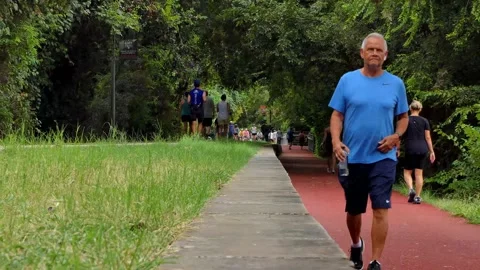 Dolly zoom of summer crowd walking and jogging in urban rails-to-trails park Vídeos de archivo 161683397