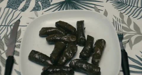 Dolmas on table with camera tilting up to man using smartphone Stock Footage 345919965