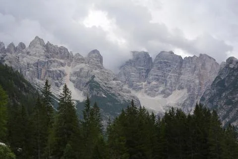 Dolomites Mountain Range Above Conifer Forest Under Cloudy Sky Stock Photos