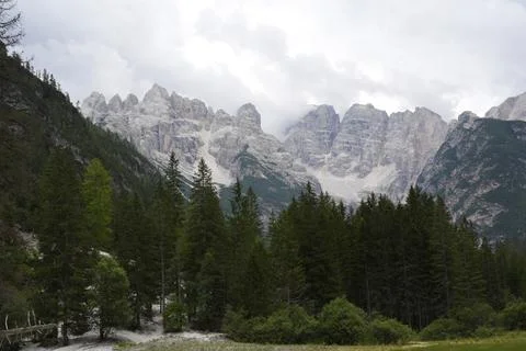 Dolomites Mountain Range Above Conifer Forest Under Cloudy Sky Stock Photos