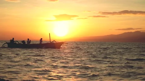 Dolphins jumping in front of boat with 3 people Stock Footage