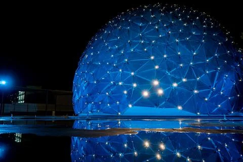 Dome shaped building, with colored lights, reflection in water, parametric .. Fotos de archivo