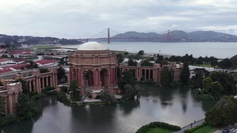 Domed palace rotunda reflects in tranquil lagoon, Golden Gate Bridge spanning Stock Footage 337746430