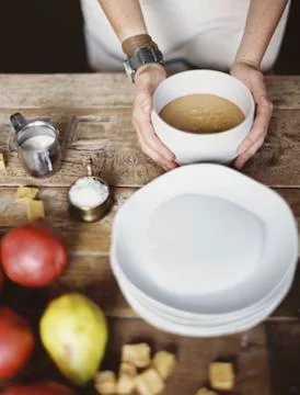 A domestic kitchen tabletop. a stack of white plates and fresh pears and a st Foto stock