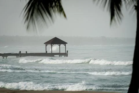 Dominicus beach at overcast day rough sea and wooden dock Stockfoto's